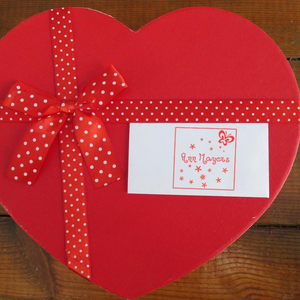 Heart-shaped red gift box with polka-dot ribbon and custom rubber stamp holiday label for Ann Mayers.