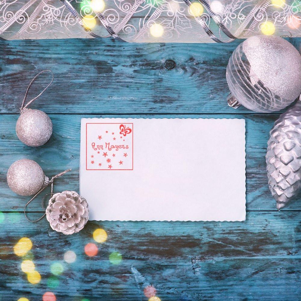 Custom rubber stamp on a holiday card with silver ornaments and festive winter decor on a blue wood background.