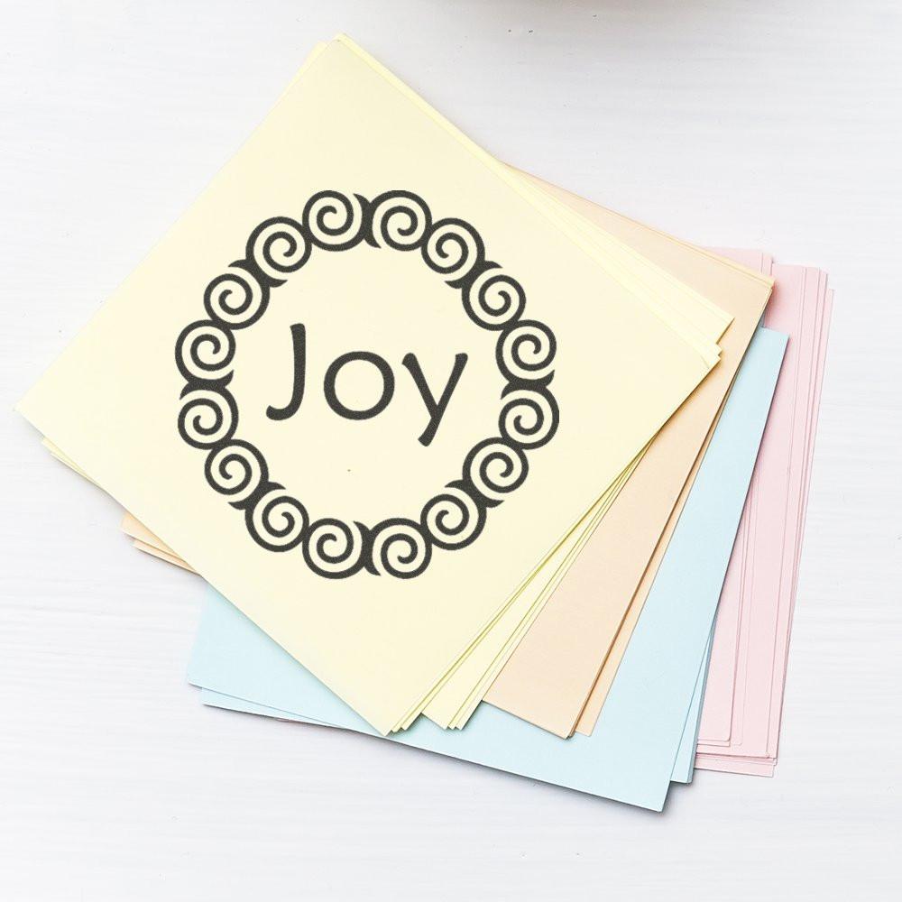 Joy rubber stamp design on pastel cards, featuring a decorative swirl wreath for handmade greeting cards and scrapbooking.