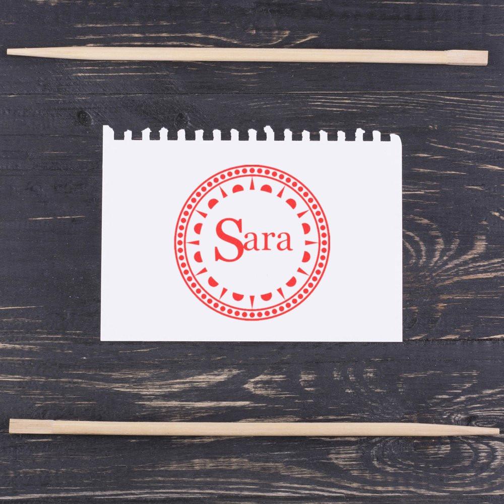 Custom rubber name stamp with Sara red circular design on paper, ideal for personalized stationery and branding.