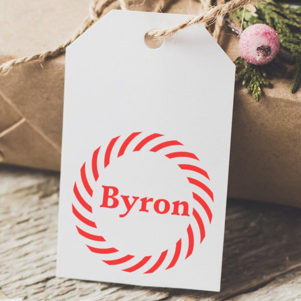 Personalized rubber stamp logo with Byron name in red on a gift tag for custom holiday packaging.