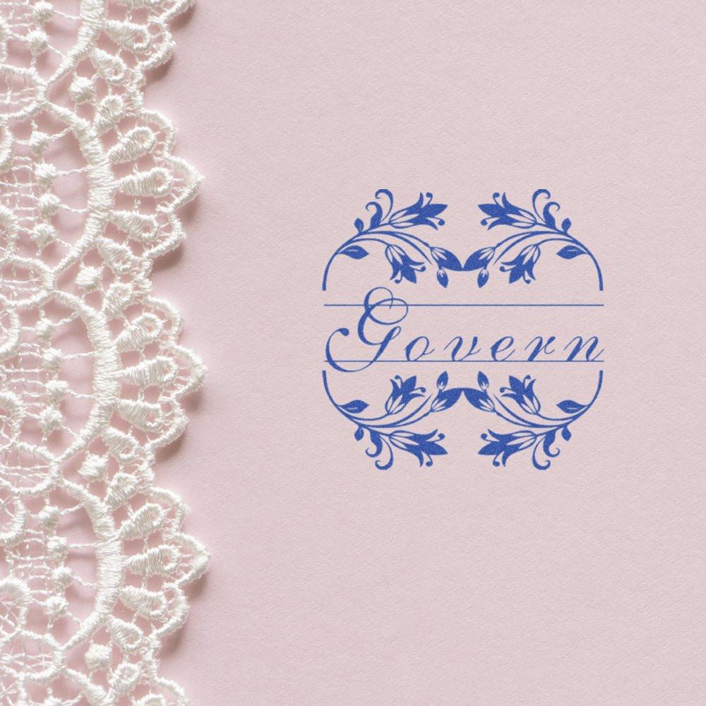 Ornate blue typographic logo on blush pink fabric background with white lace, representing decorative brand identity design.