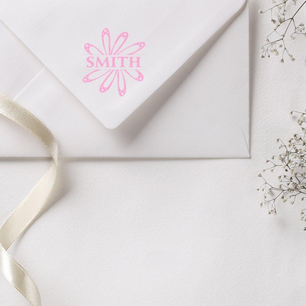 Personalized rubber stamp monogram SMITH on a white wedding envelope with pink floral design.