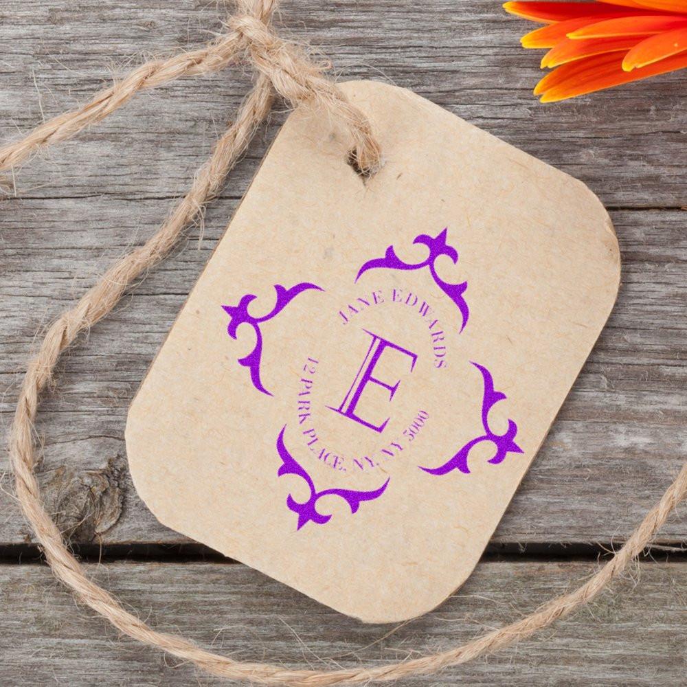 Custom rubber stamp monogram on kraft gift tag for wedding or branding, shown in purple ink on rustic wood background.