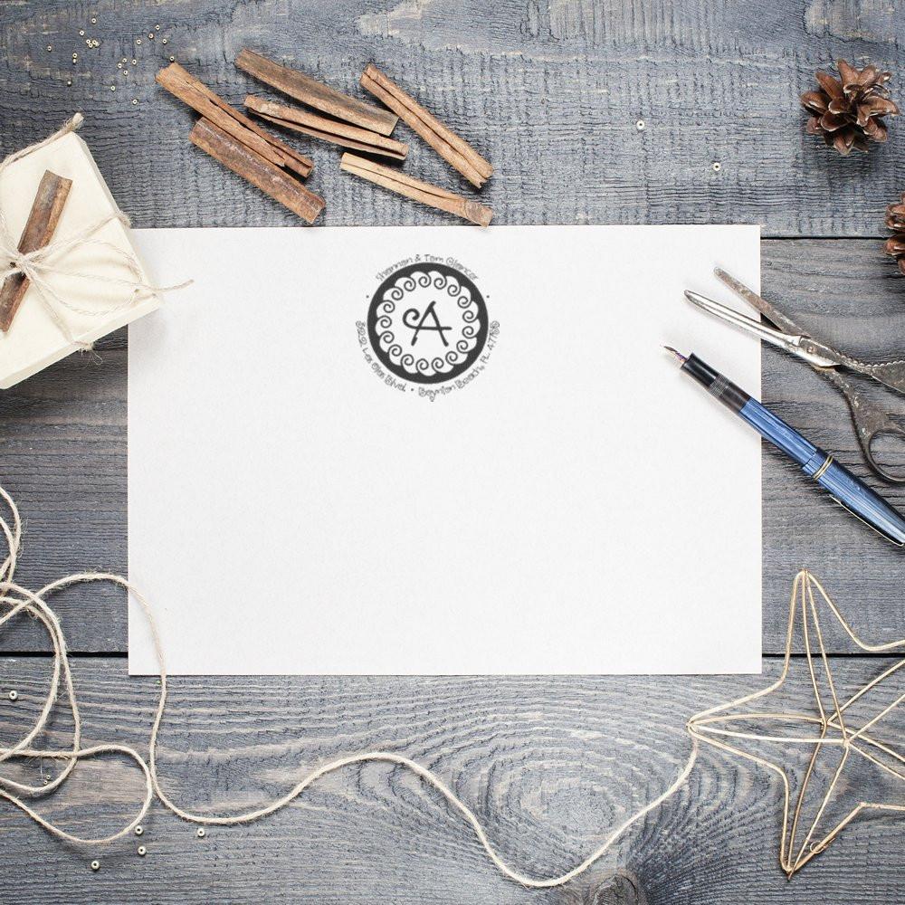 Custom monogram rubber stamp on wedding invitation stationery, shown on blank paper with rustic craft supplies.