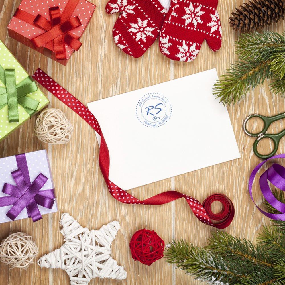 Personalized holiday rubber stamp on white card with gift wrap, ribbons, and festive decor for Christmas packaging and branding.