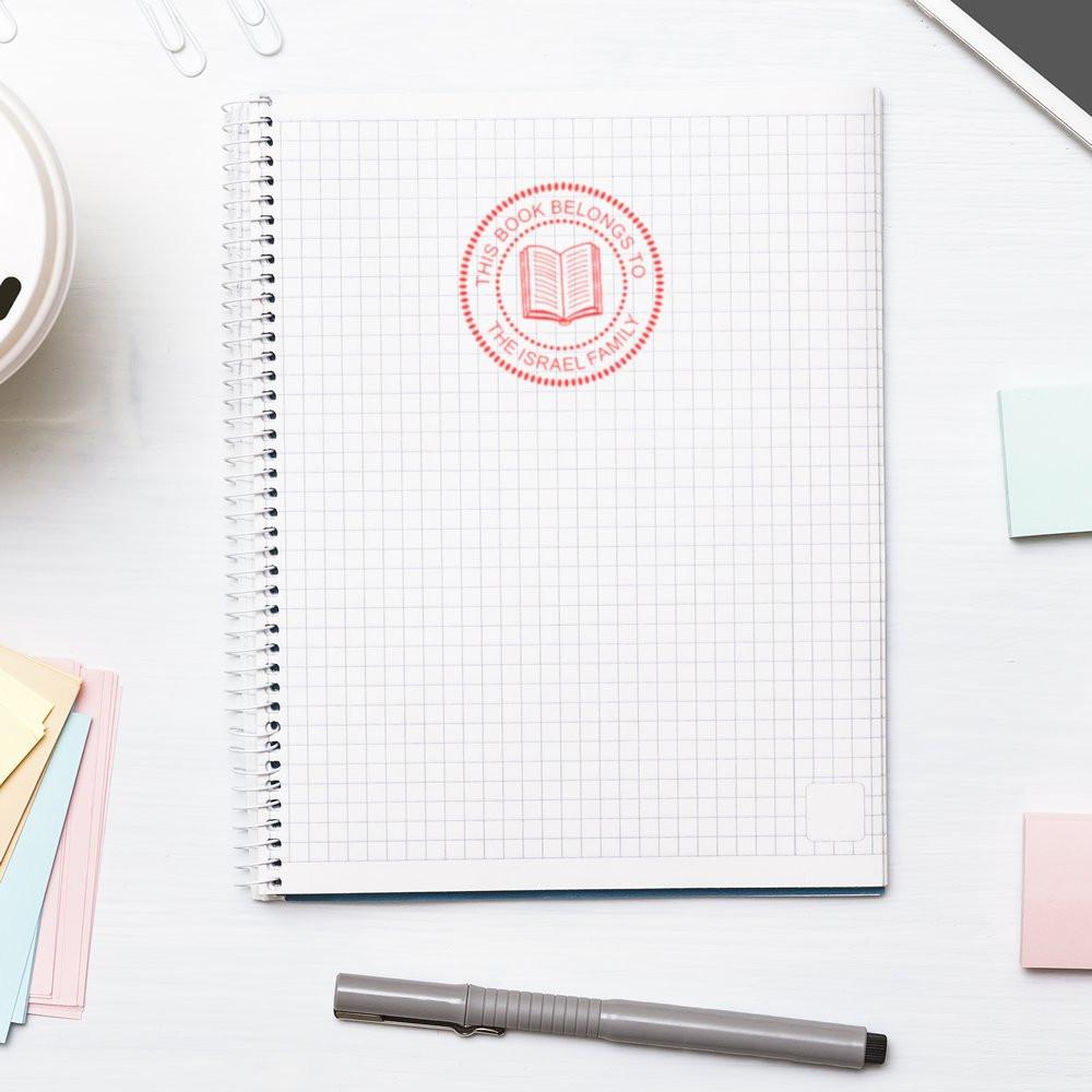 Custom book belongs to stamp on notebook, showcasing a personalized rubber stamp for family book labels and school supplies.