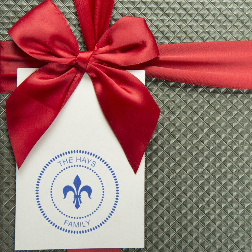 Custom rubber stamp gift tag with The Hays Family fleur-de-lis logo and red satin bow.