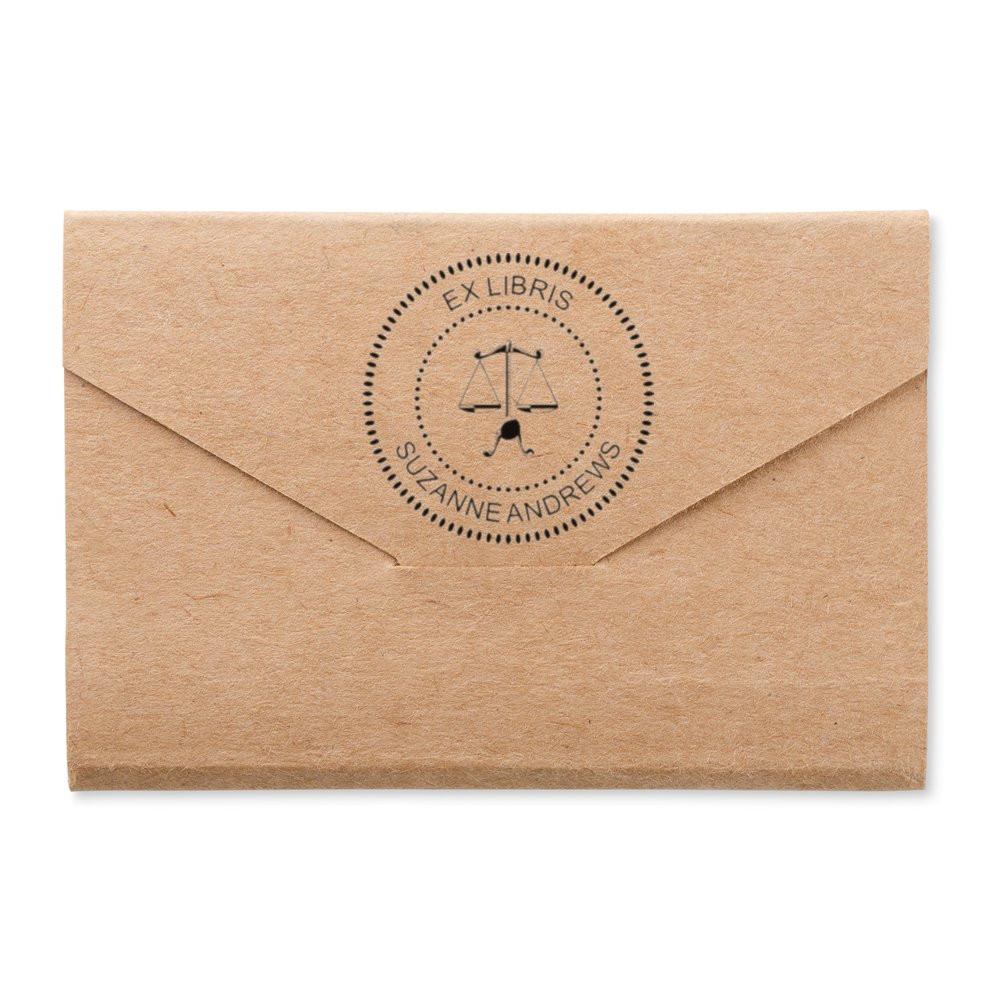 Custom ex libris rubber stamp on kraft envelope, featuring a scales of justice design and Suzanne Andrews bookplate name.