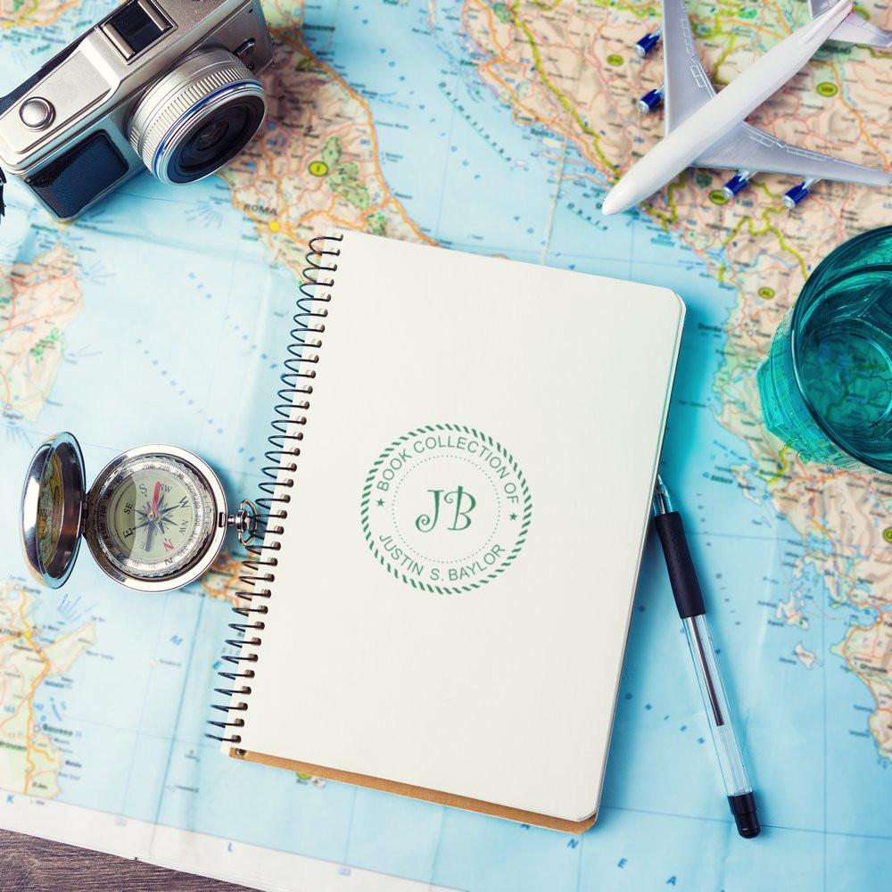 Custom rubber stamp on a travel journal notebook, featuring personalized bookplate branding for a book collection.