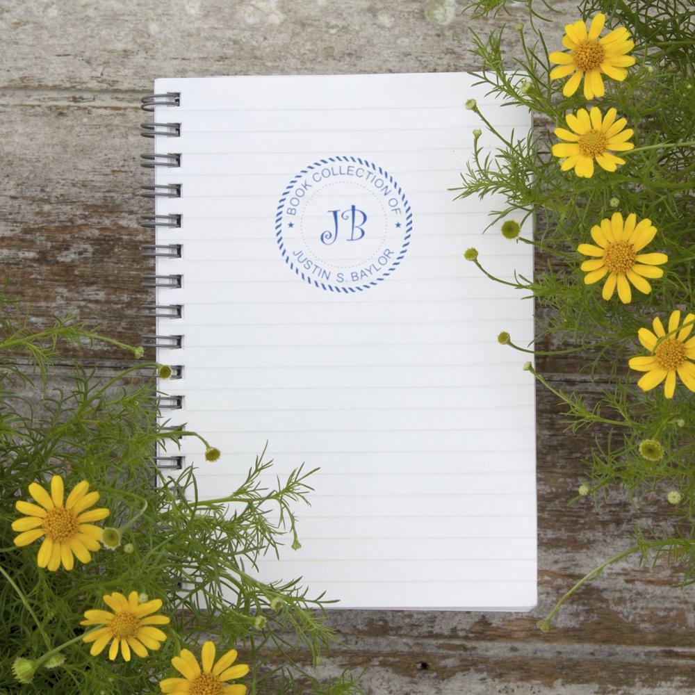 Custom monogram book collection rubber stamp on notebook, perfect for personal library book ownership.