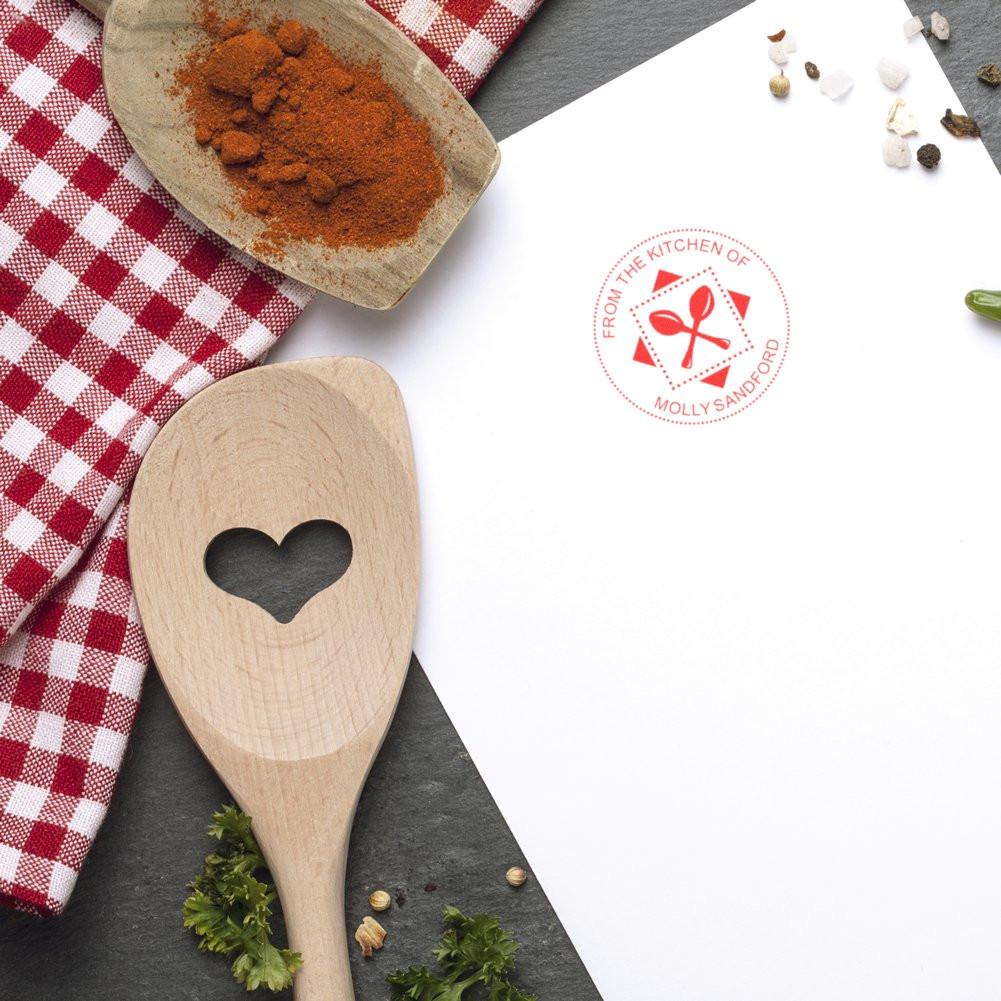 Custom kitchen rubber stamp impression on recipe paper, with spoon icon and From the Kitchen of Molly Sandford text.