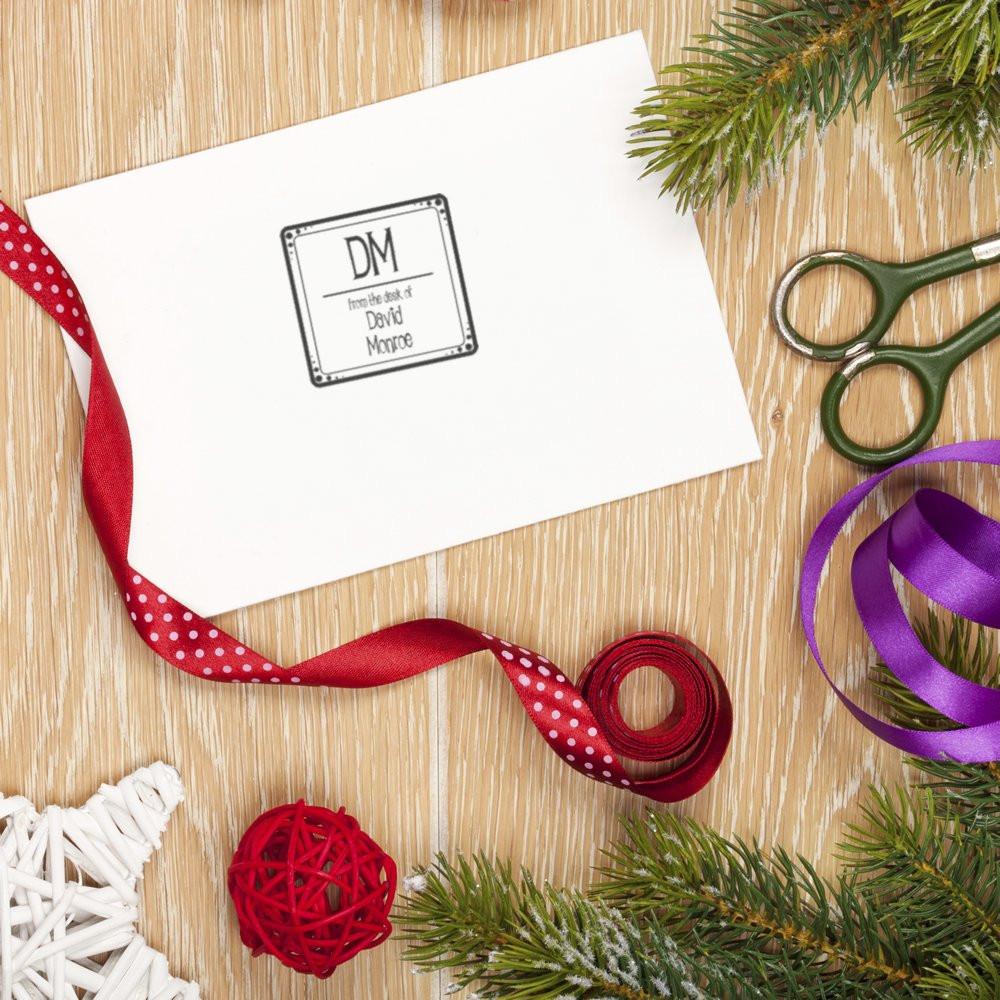 Personalized rubber stamp featuring from the desk of initials DM on stationery, styled with ribbons and craft supplies.