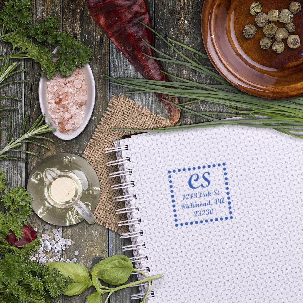 Personalized return address rubber stamp imprint on notebook, styled with herbs and rustic tabletop decor.