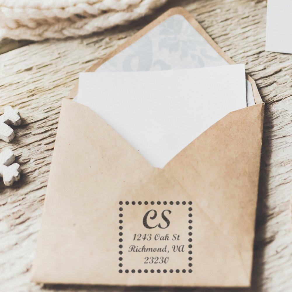 Custom return address rubber stamp on a kraft envelope with monogram initials and mailing address.