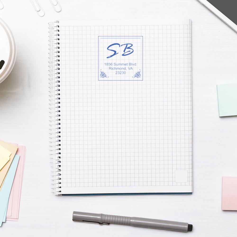 Custom rubber address stamp impression with monogram on notebook, ideal for personalized stationery and business branding.