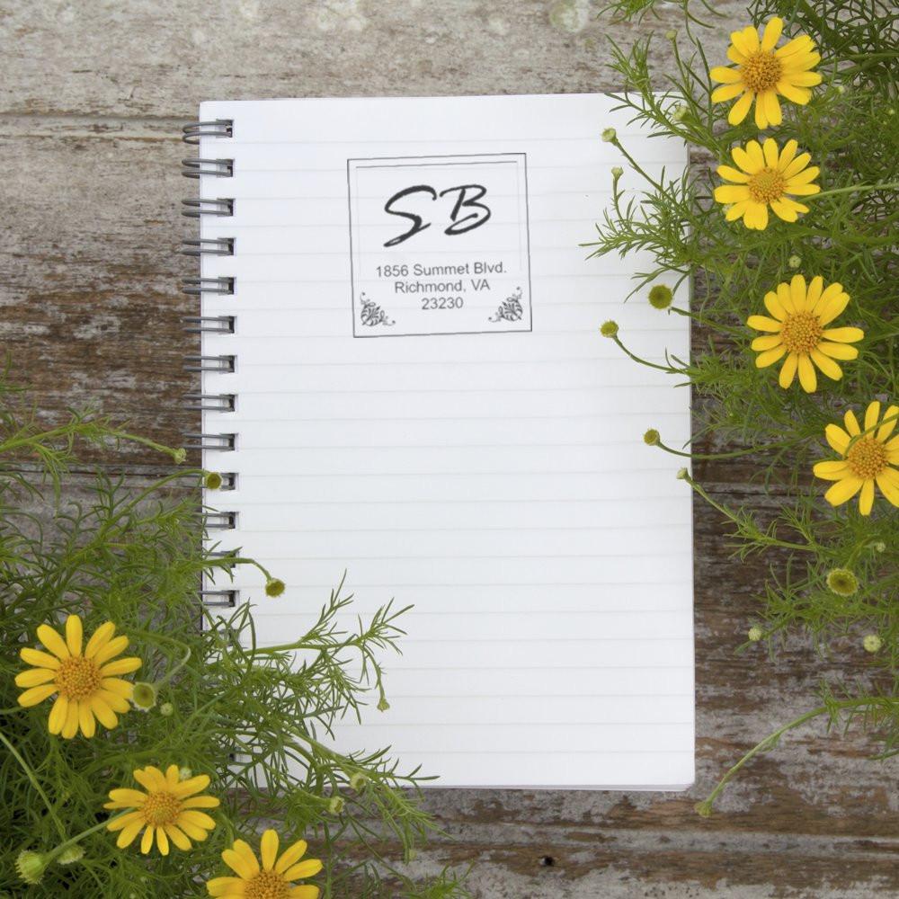 Personalized return address rubber stamp with monogram on a notebook, styled for stationery branding.