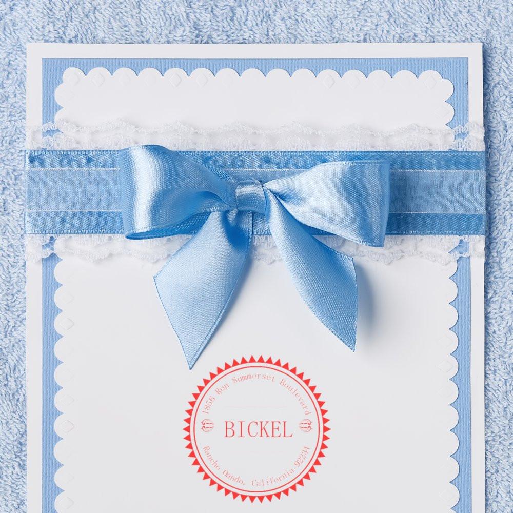 Custom return address rubber stamp on elegant blue wedding stationery with satin bow.