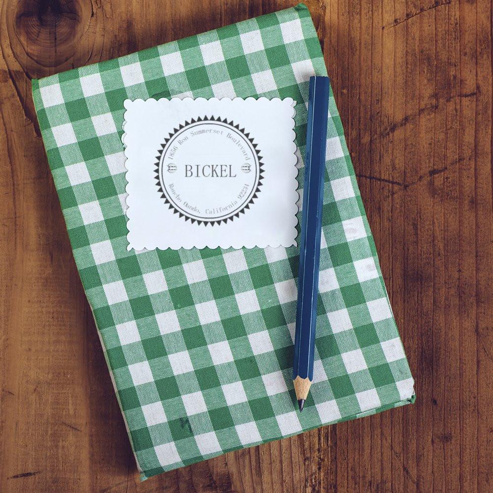 Personalized custom rubber stamp seal on a gingham notebook, with BICKEL name design for stationery branding.