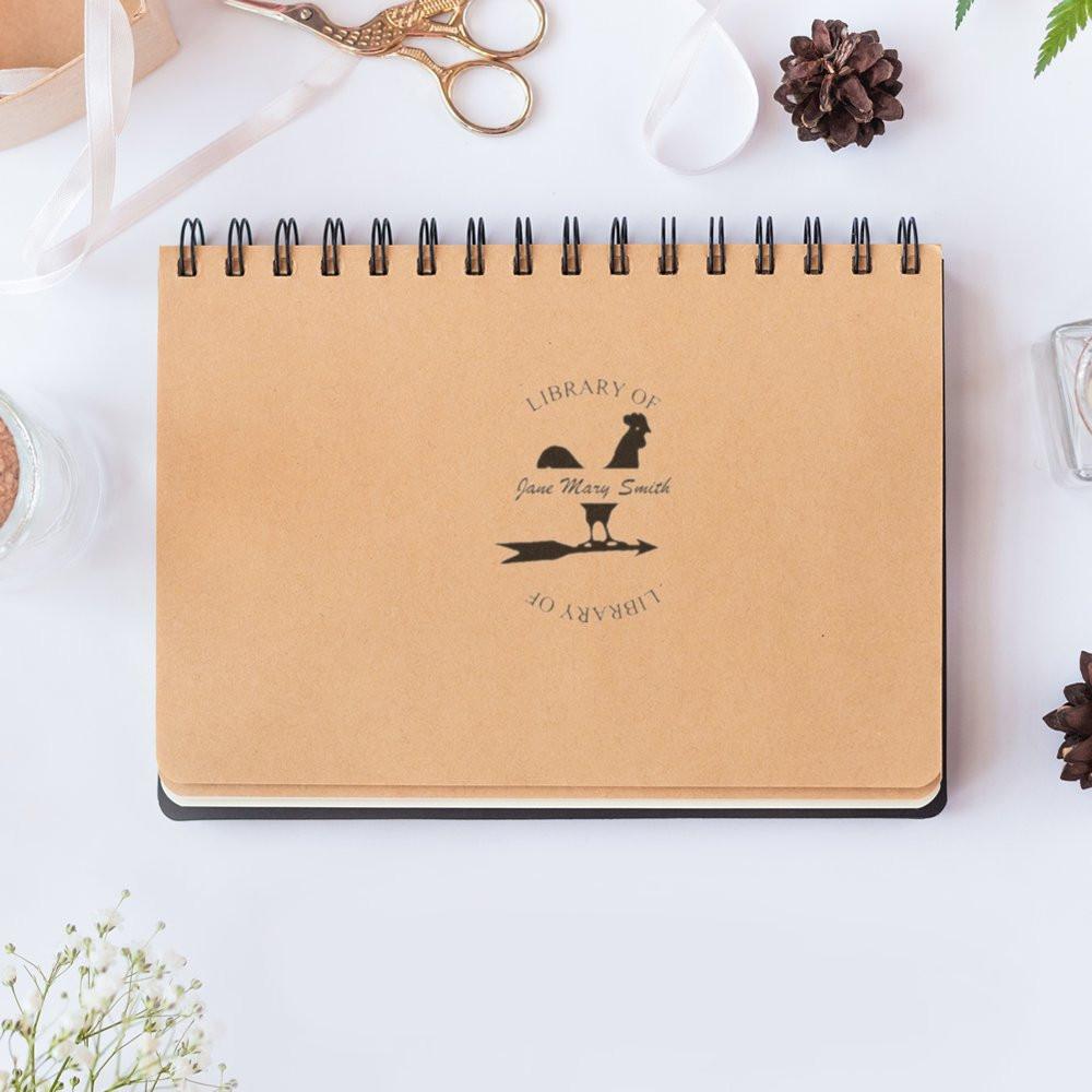 Personalized library rubber stamp on spiral notebook, perfect for bookplates, books, and custom stationery.