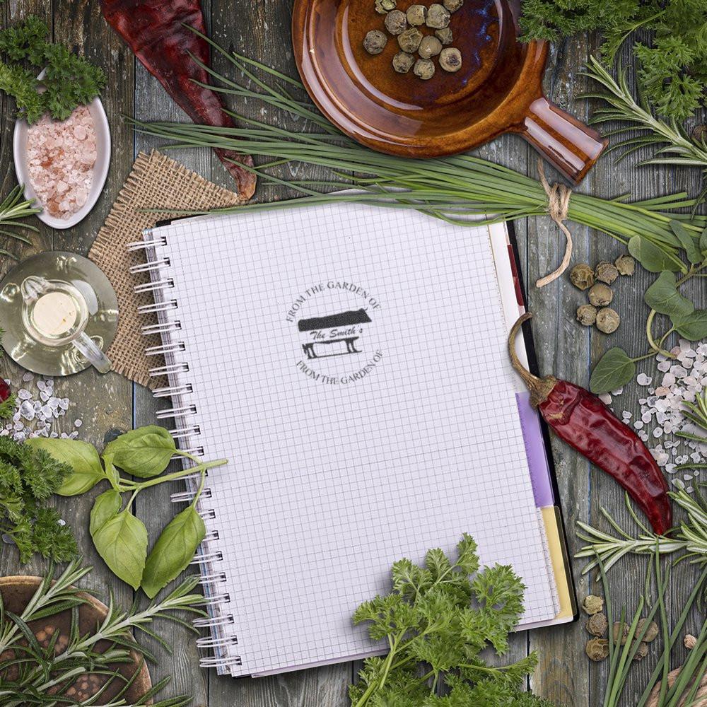 Garden-themed rubber stamp on a notebook page, surrounded by herbs and spices, for custom botanical and culinary branding.
