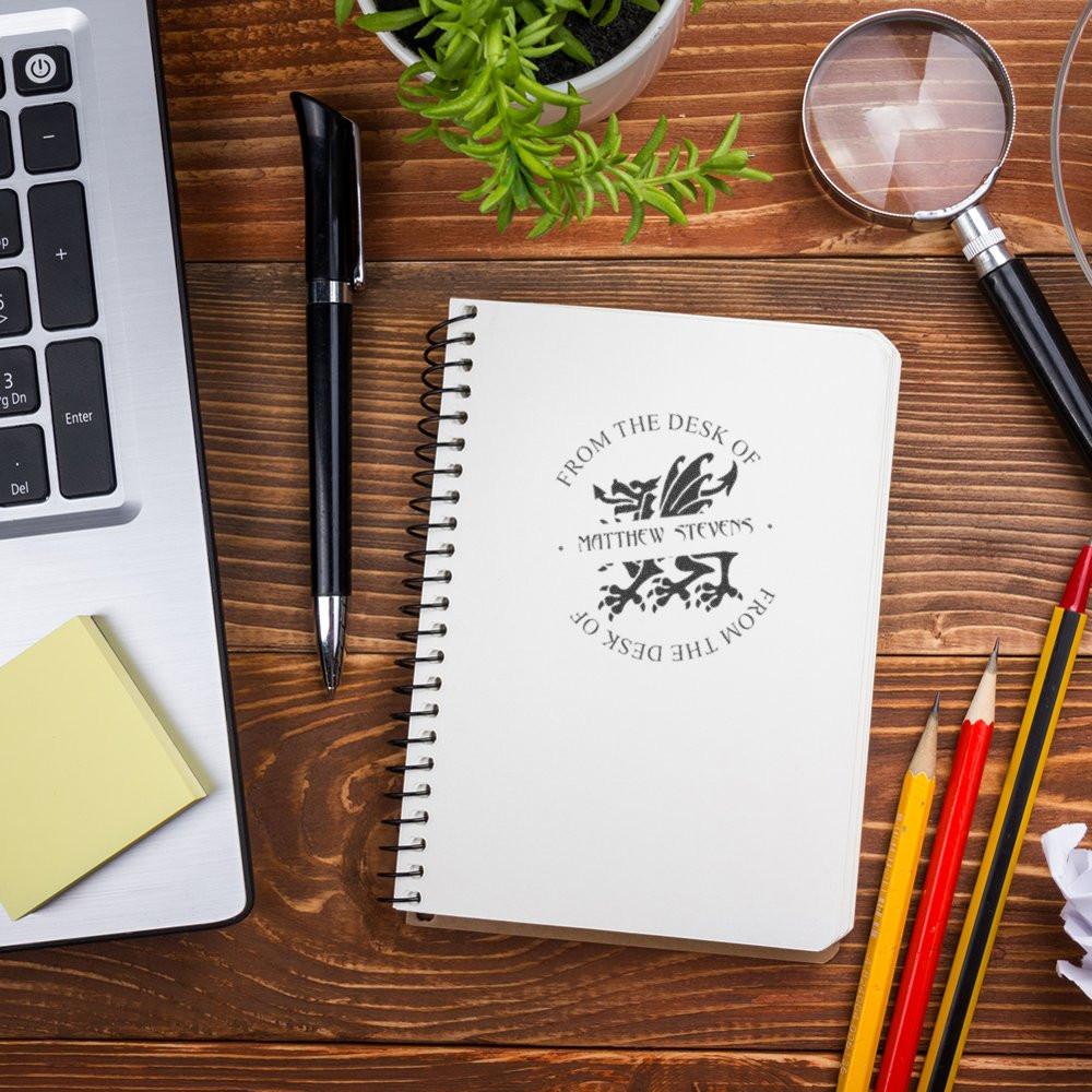 Personalized rubber stamp imprint on notebook, featuring From the Desk of Matthew Stevens for custom office branding and stationery.