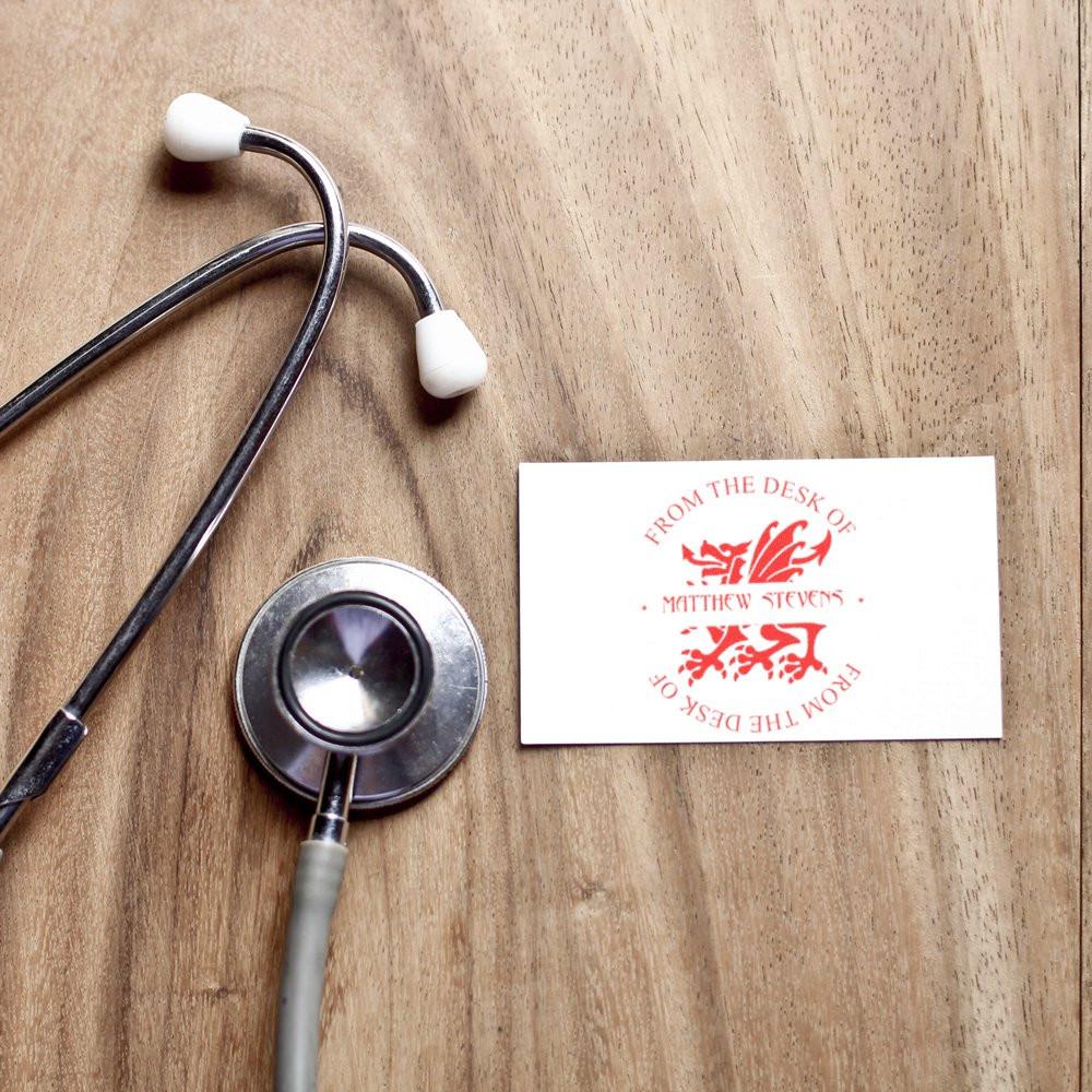 Custom rubber stamp impression on a business card beside a stethoscope for medical professional branding.