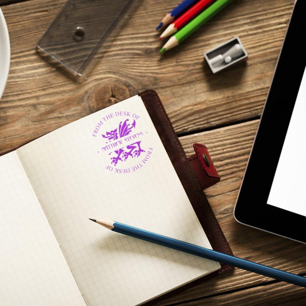 Custom rubber desk stamp on a notebook page for personalized stationery, office branding, and sender identification.
