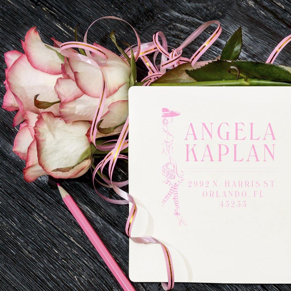 Angela Kaplan personalized luxury wedding invitation card on dark wood with pink roses and satin ribbons, showing name and address.