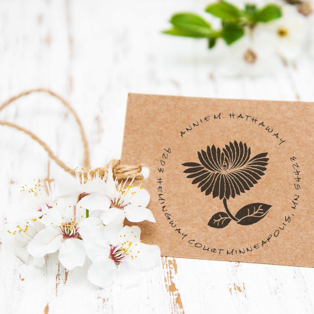 Custom floral rubber stamp on kraft gift tag with twine and white flowers for handmade packaging.