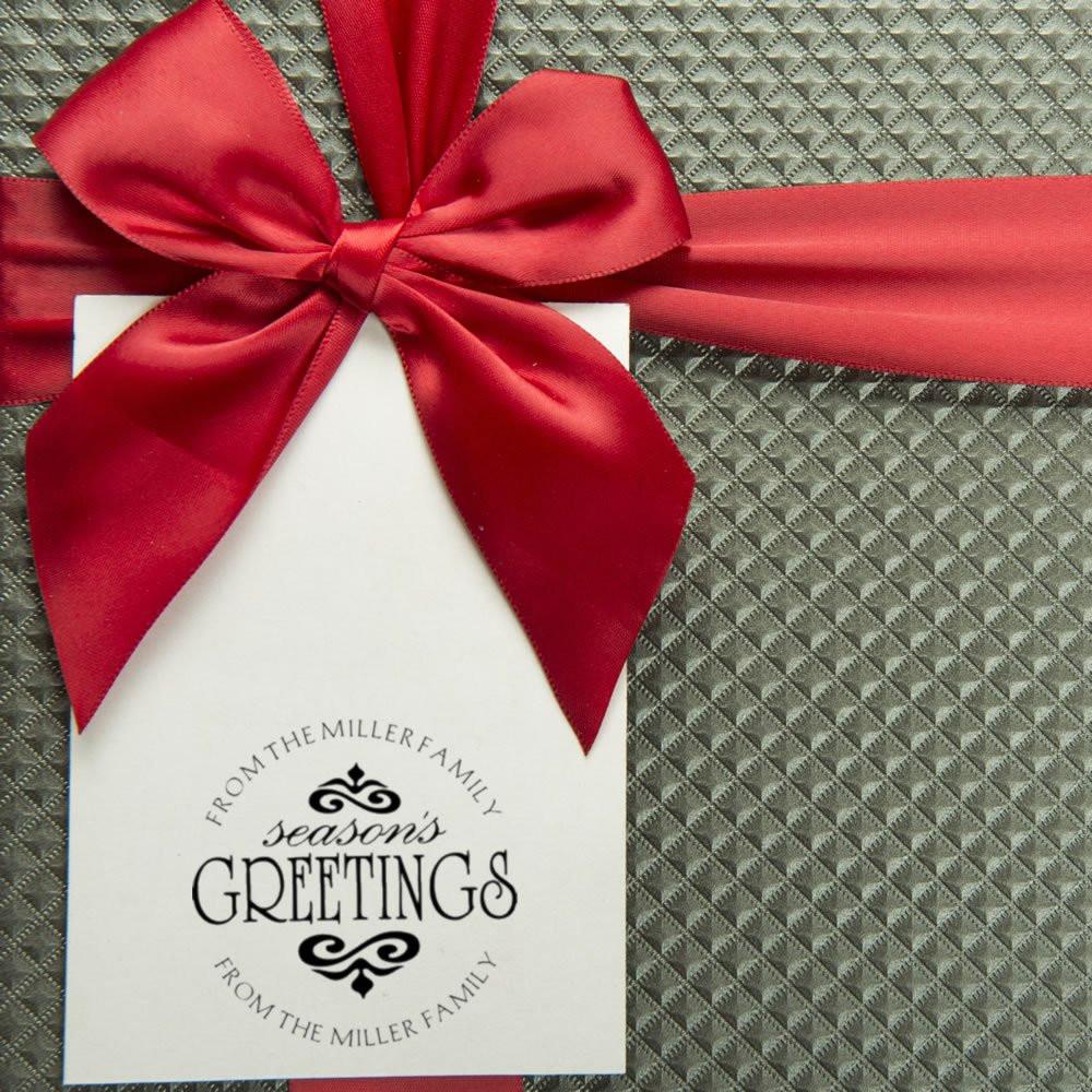 Custom rubber stamp holiday gift tag with Seasons Greetings and From the Miller Family on a white card with red bow.