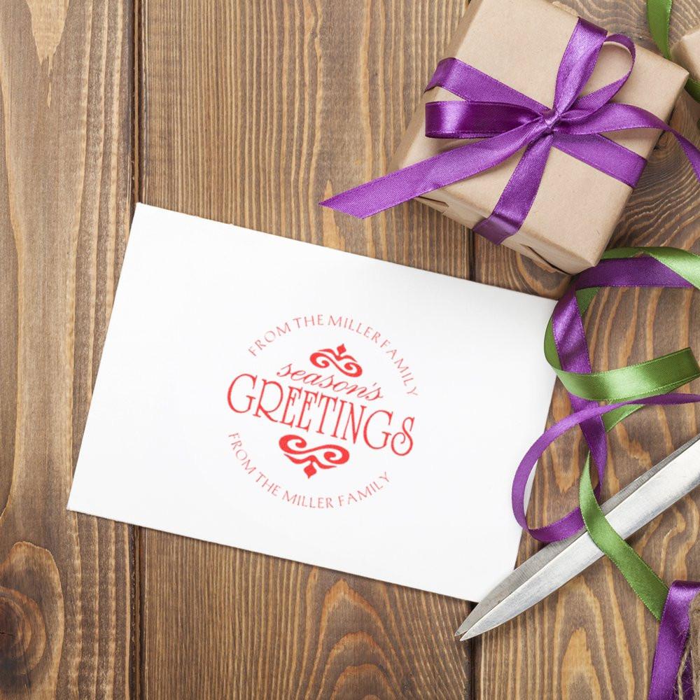 Custom rubber stamp holiday card reading Seasons Greetings from the Miller family, with wrapped gifts and ribbon.