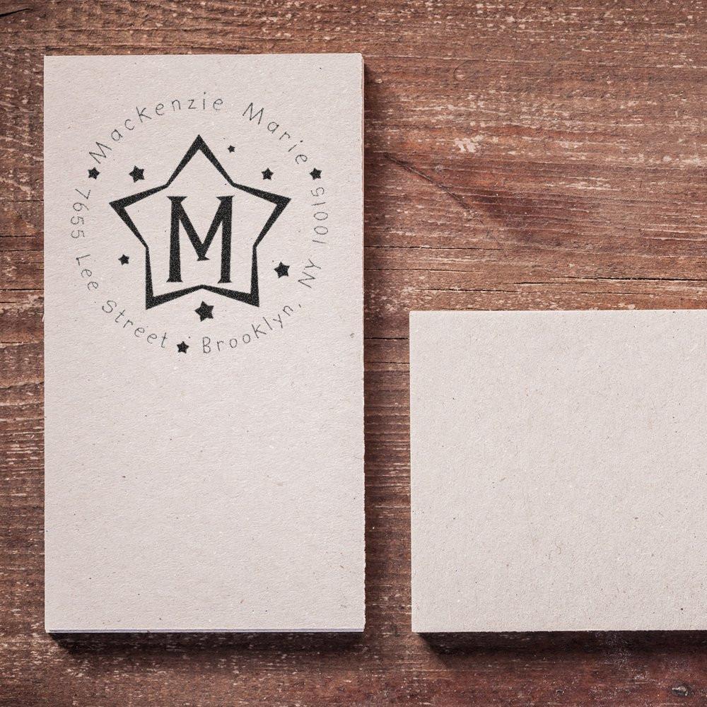 Print design business card with star monogram 'M' for Mackenzie Martin, Brooklyn NY address, beside a blank card on wood.