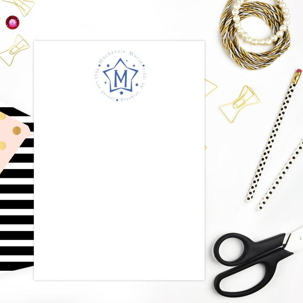Blank greeting card mockup with blue monogram logo, styled with stationery, pearl bracelet, and gold clips on a white background