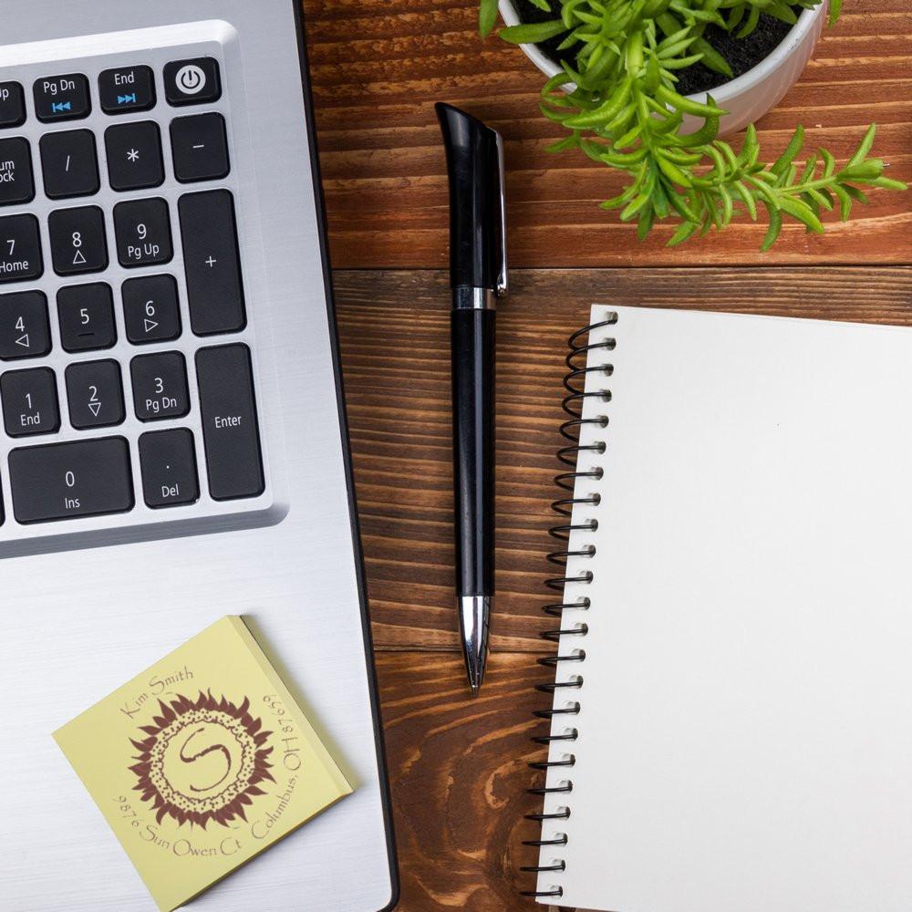 Custom rubber stamp with logo impression on a desk beside laptop, pen, and notebook for business branding.