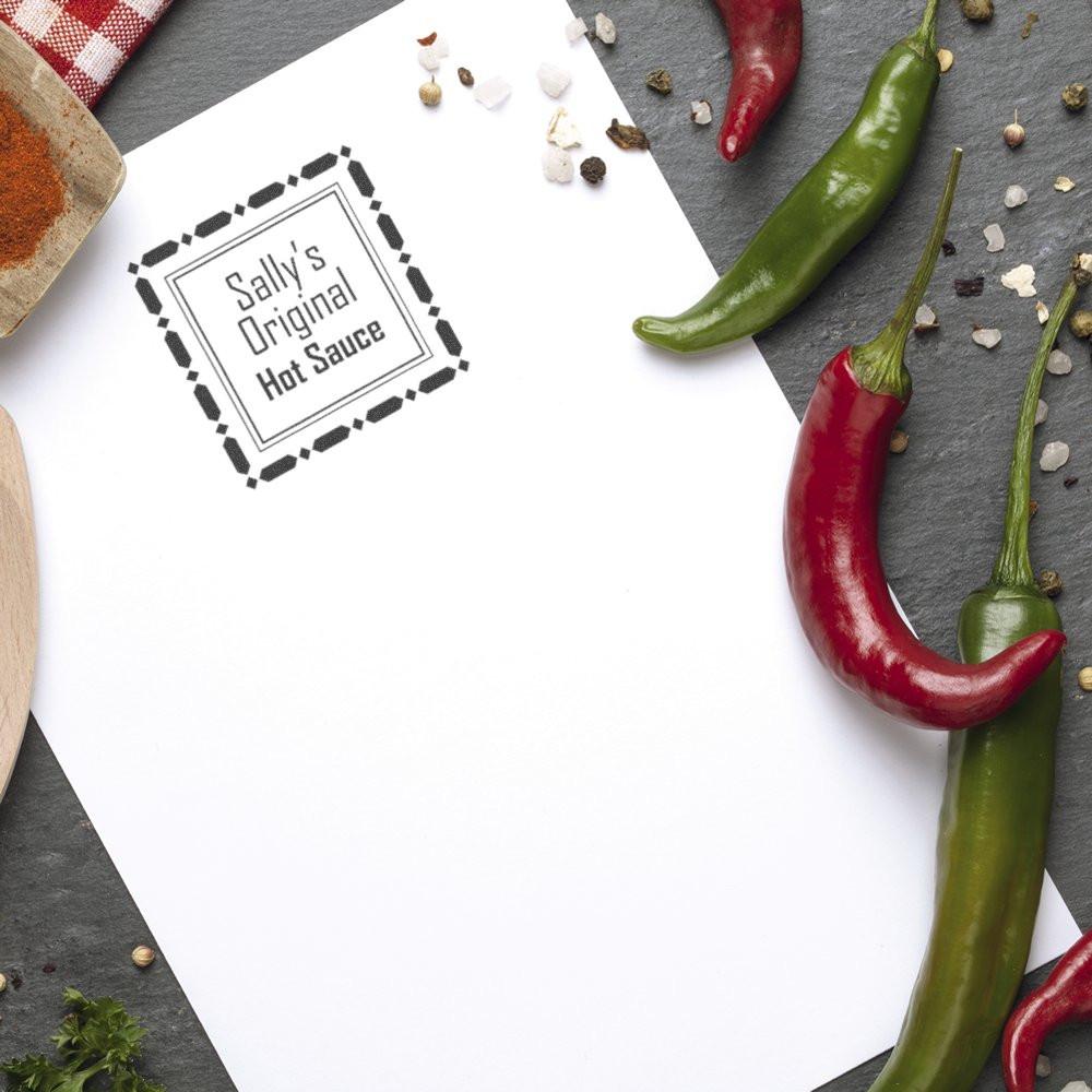 Custom rubber stamp for hot sauce branding, stamped Sallys Original Hot Sauce on paper with chili peppers and spices.