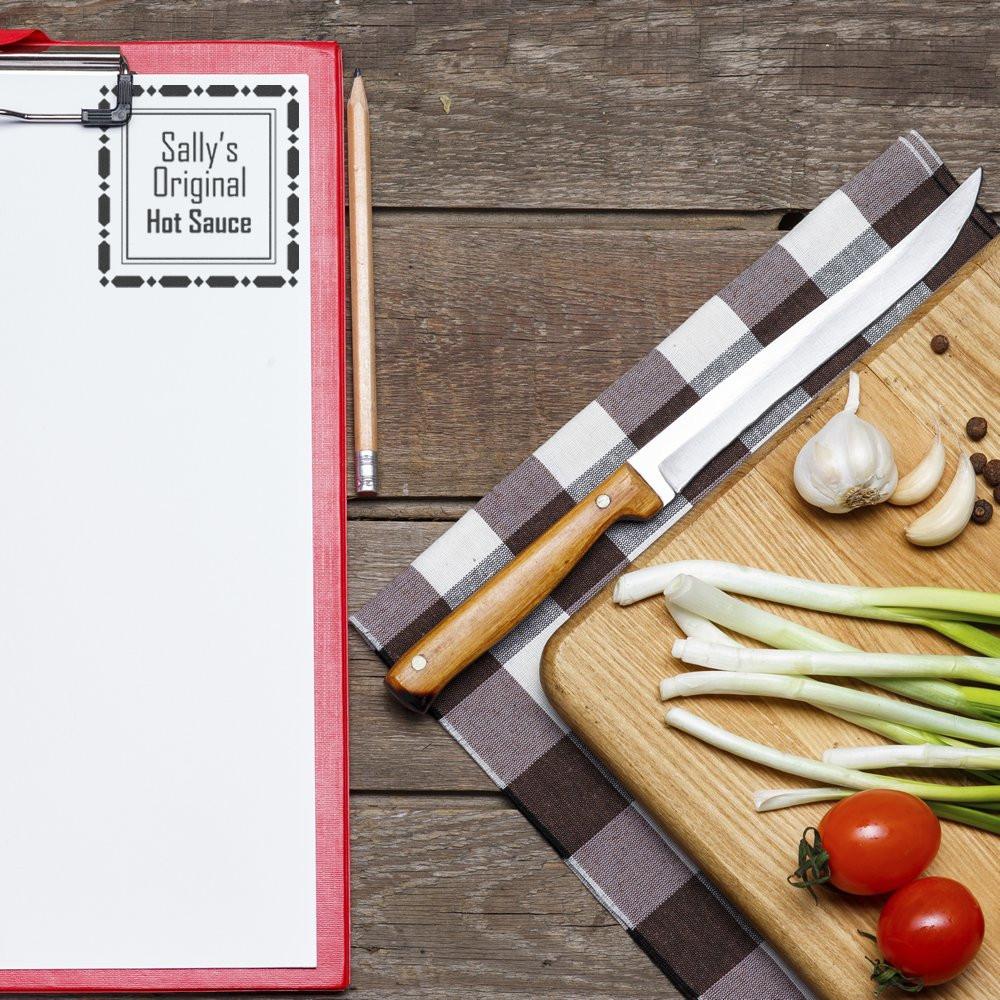 Custom rubber stamp label on recipe clipboard for Sallys Original Hot Sauce, with garlic, scallions, and tomatoes for food branding.