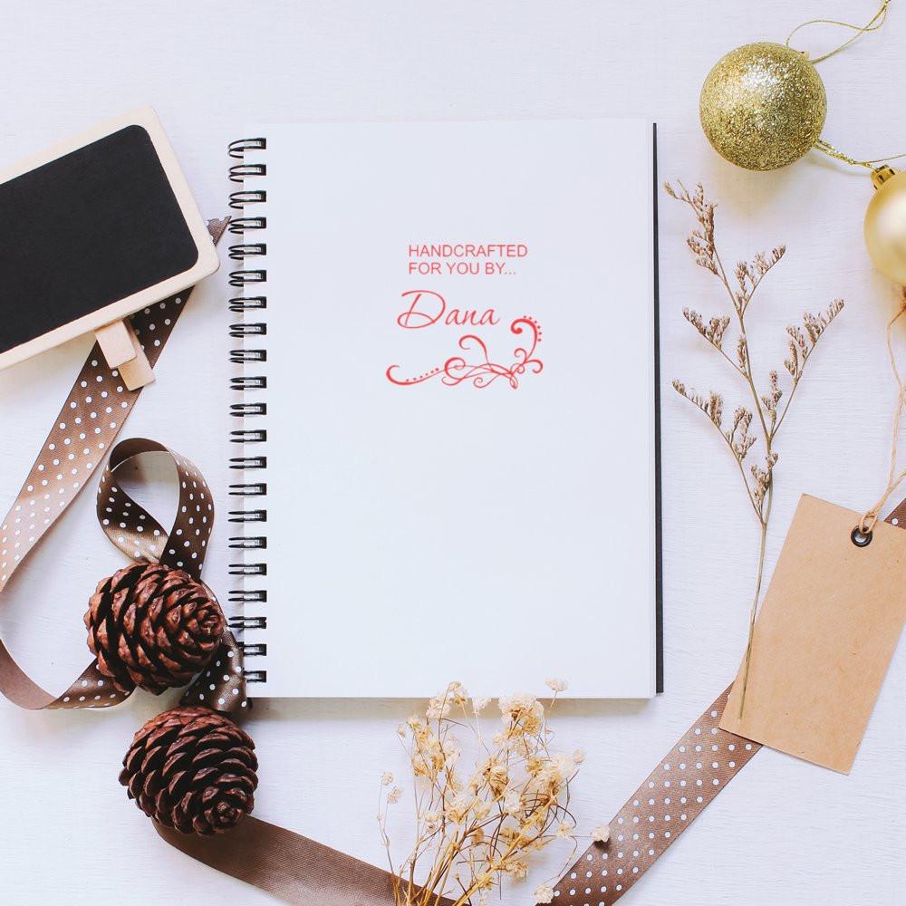 Custom rubber stamp reading Handcrafted for You by Dana on a spiral notebook, ideal for handmade business branding.