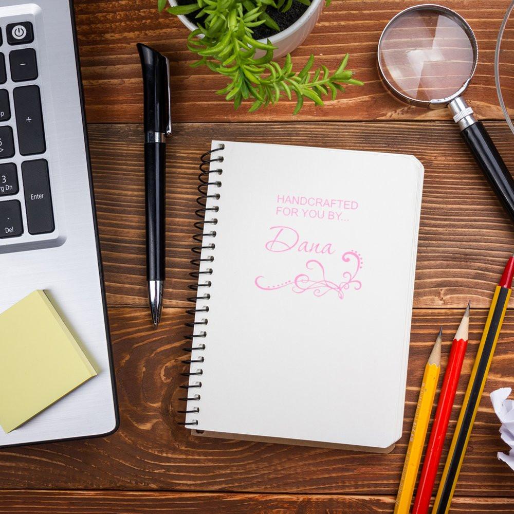 Personalized rubber stamp imprint reading Handcrafted for you by Dana on a notebook, ideal for handmade business branding.