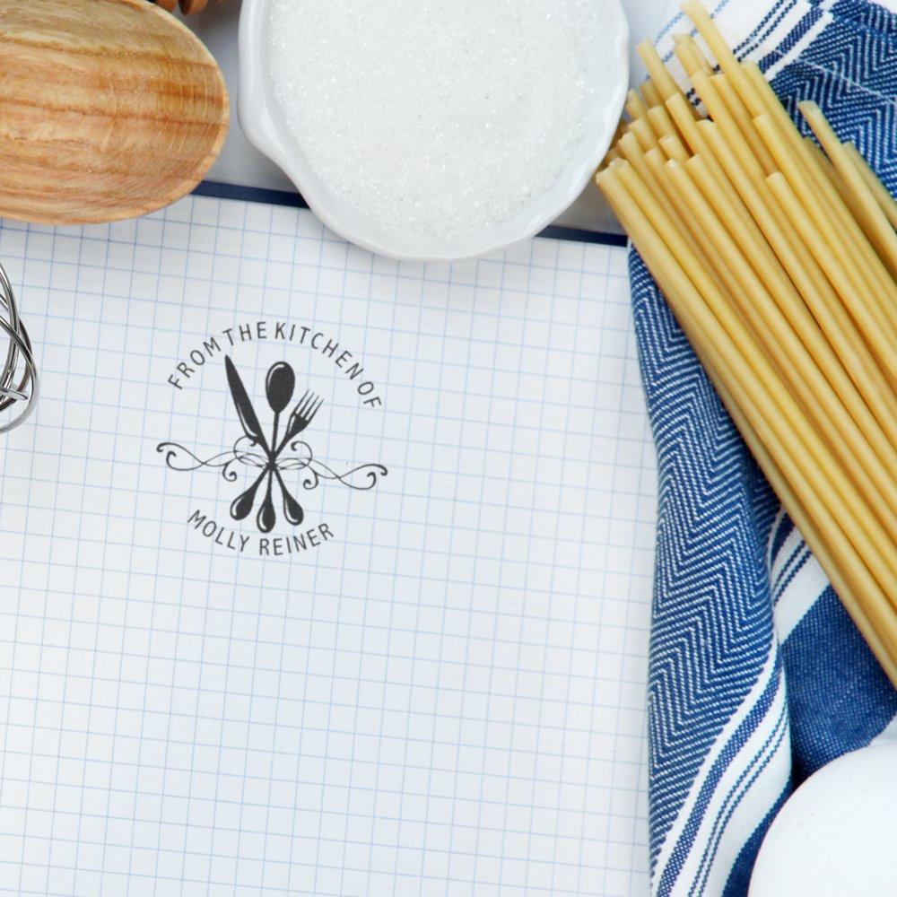 Custom kitchen rubber stamp with utensils and name Molly Reiner on grid paper, ideal for personalized recipe labels and stationery.