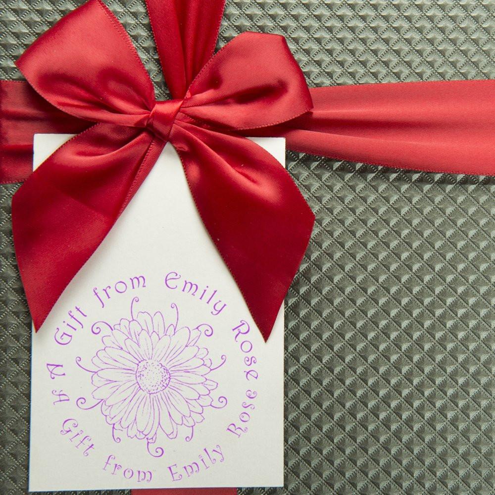 Custom floral rubber stamp on a gift tag with red ribbon bow, ideal for personalized gift wrapping and packaging.