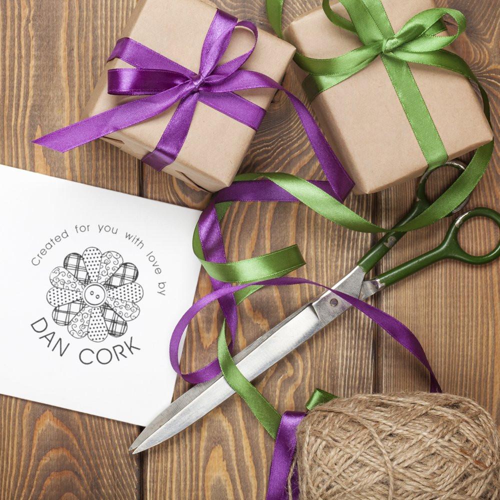 Dan Cork gift packaging with kraft boxes tied in purple and green ribbons, including custom tag and scissors on rustic wood.
