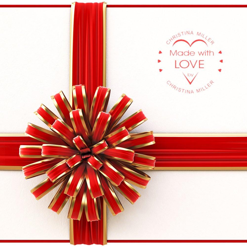 Custom rubber stamp reading Made with Love on red and gold gift wrap with ribbon bow for handmade packaging.