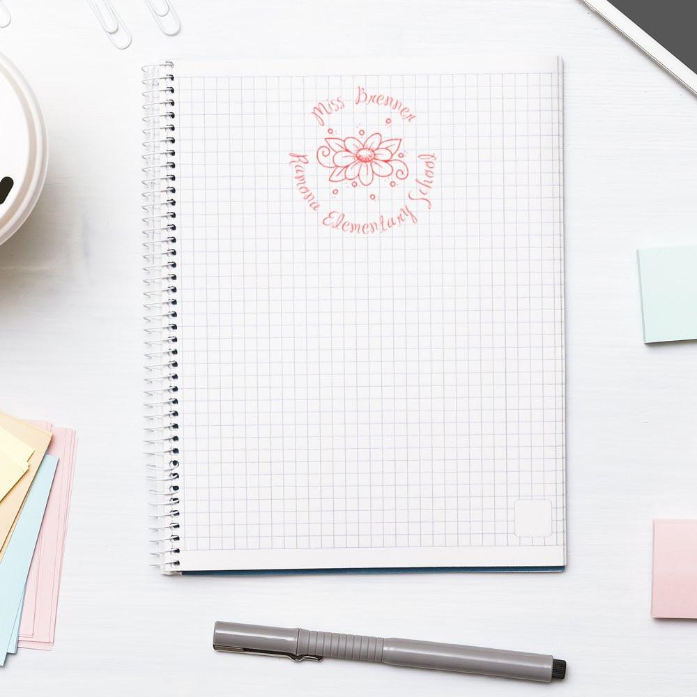Custom floral rubber stamp on a notebook, personalized teacher stamp for classroom supplies and school branding.