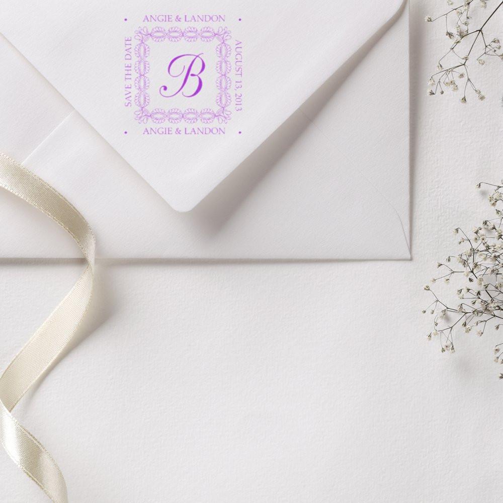 Custom wedding rubber stamp with monogram and save the date on a white envelope for elegant invitations.
