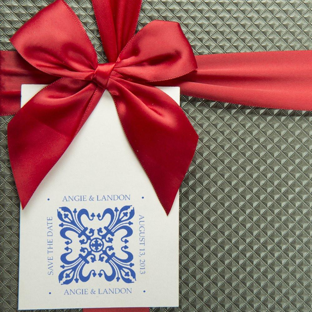 Personalized wedding save the date rubber stamp with ornate blue monogram for Angie and Landon, styled with a red ribbon.