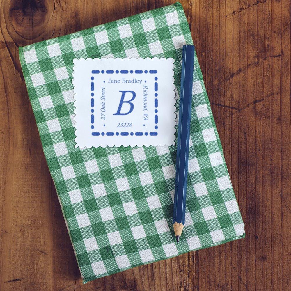 Custom return address rubber stamp on green gingham notebook with pencil, featuring monogram and address details.