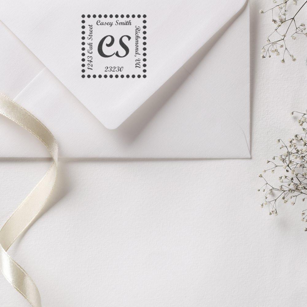 Custom return address rubber stamp on a white envelope, featuring monogram initials for wedding invitations, stationery, or business mail.