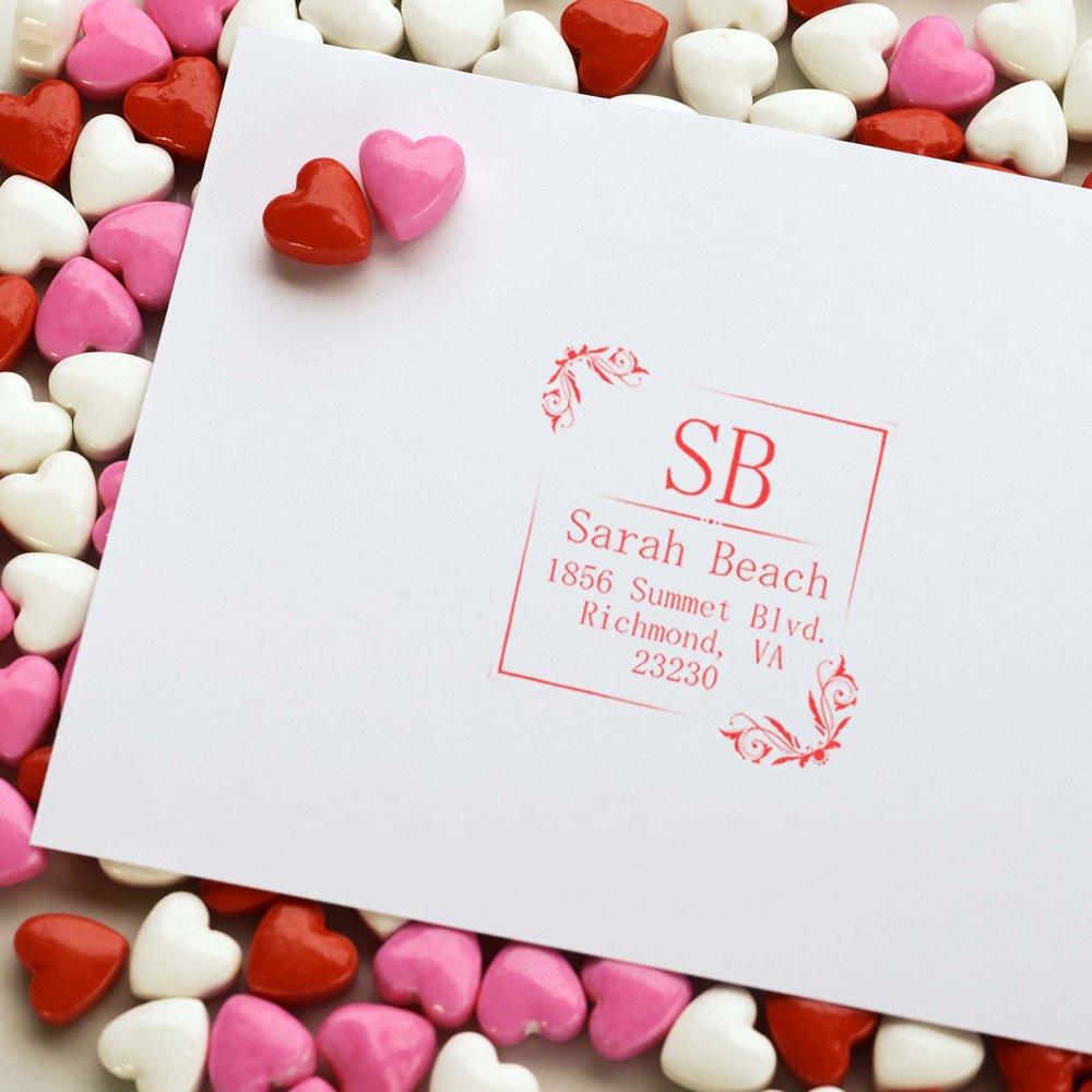 Personalized return address rubber stamp for wedding stationery, shown on paper with heart candies and a custom monogram address.