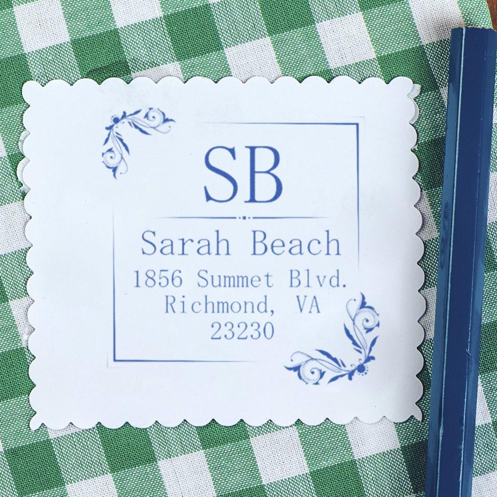 Custom address rubber stamp with monogram and floral corners, showing a personalized return address in blue ink.